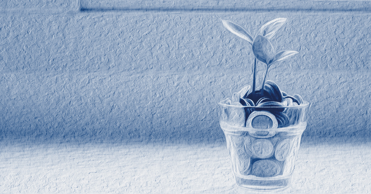 A young plant sprouting out of a glass pot filled with coins.